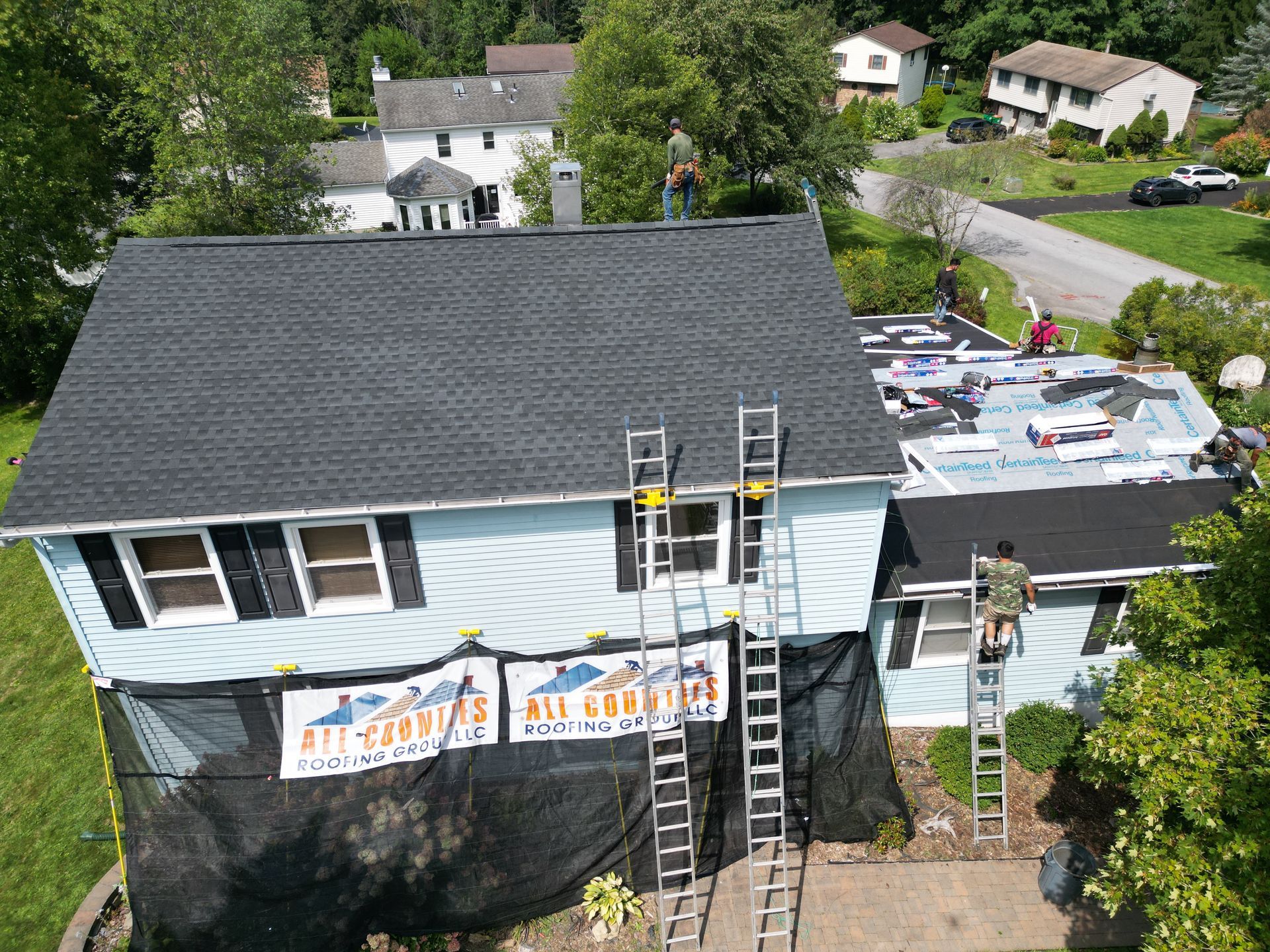 An aerial view of a blue house that is getting a new roof