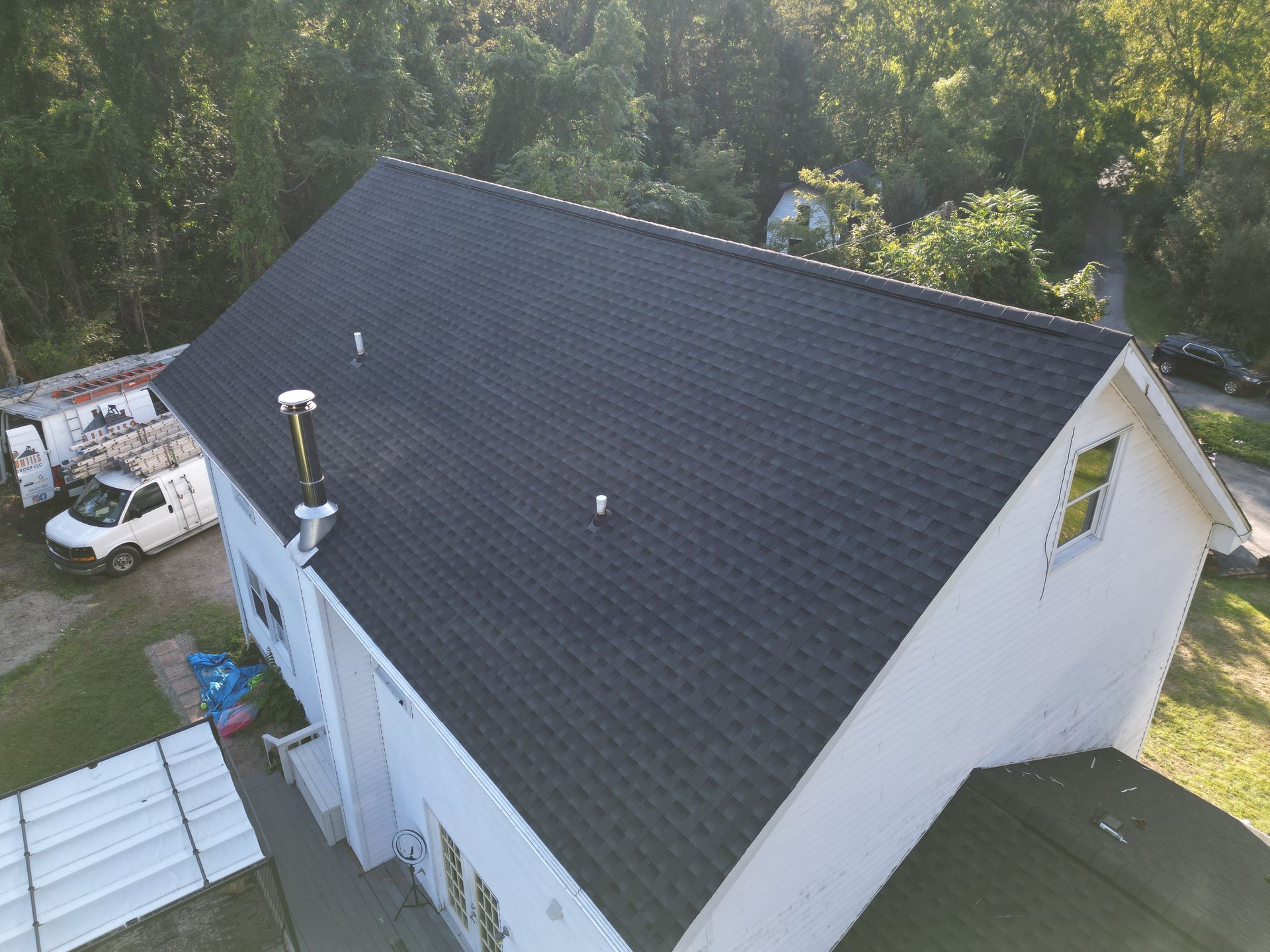 An aerial view of a white house with a black roof replacement