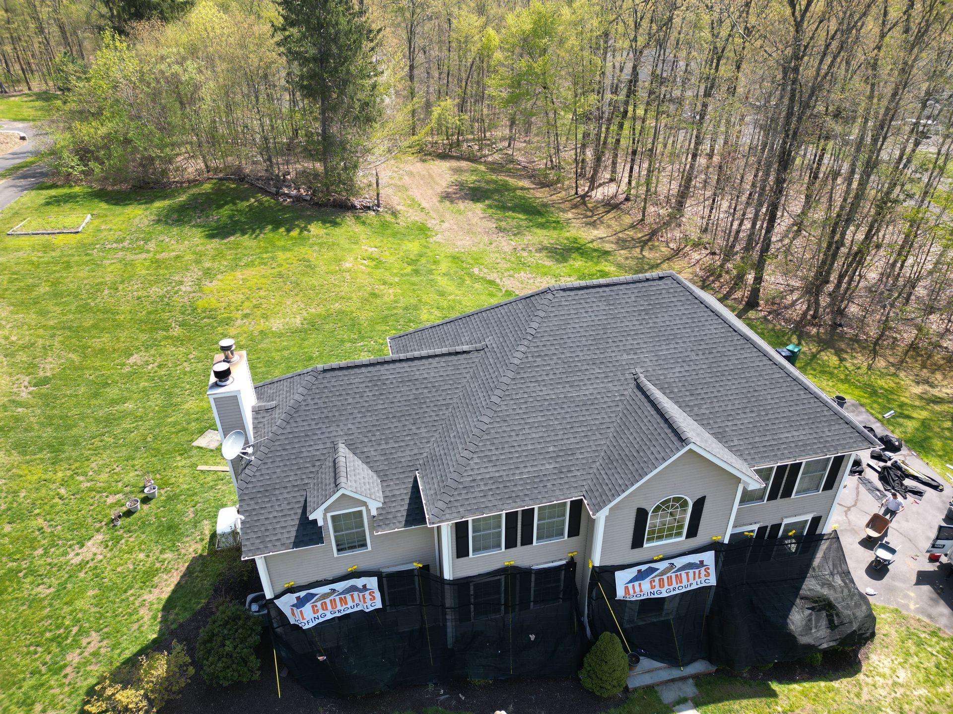An aerial view of a large house with a new roof by All Counties Roofing