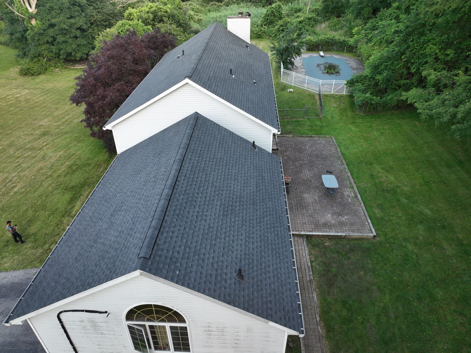 An aerial view of a white
house with a black roof replacement
