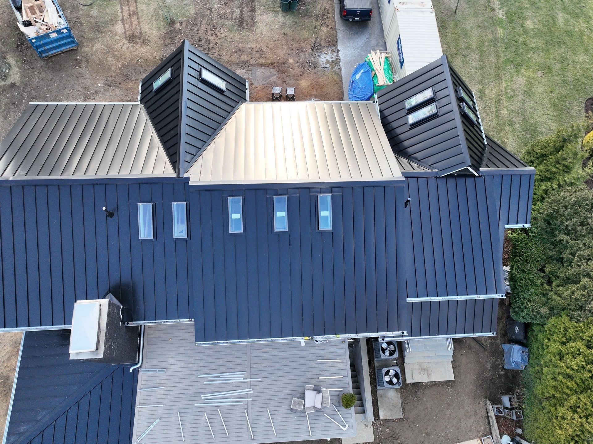 An aerial view of a house with a black metal roof installation with skylights