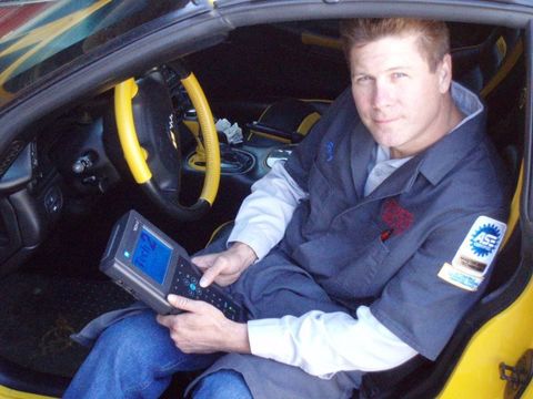 A man is sitting in a yellow car holding a tablet