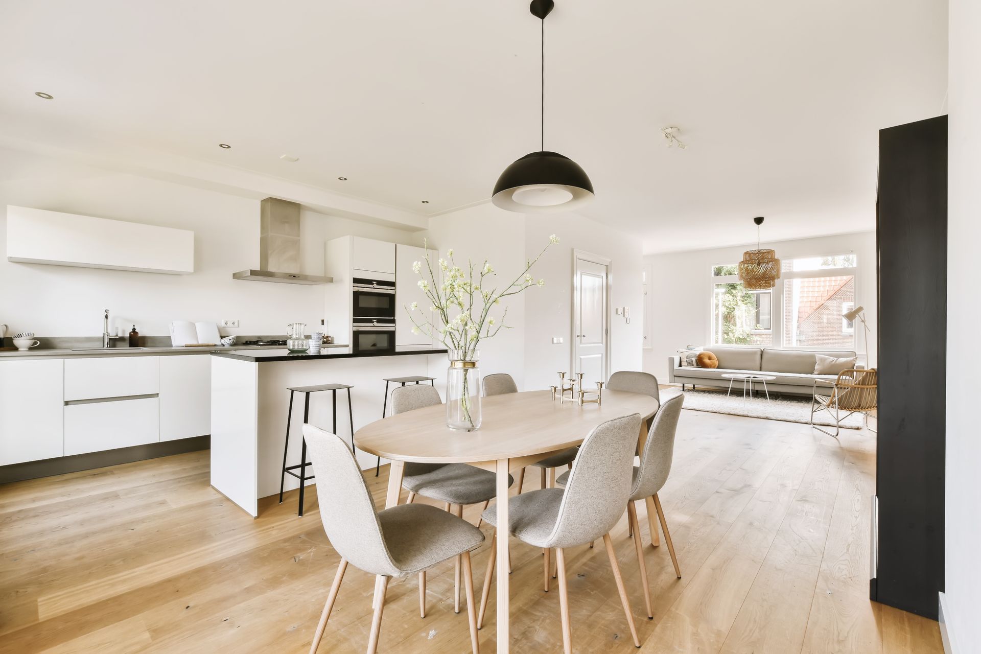 Modern kitchen and dining area with light wood floors, white cabinets, and a dining table with chairs.