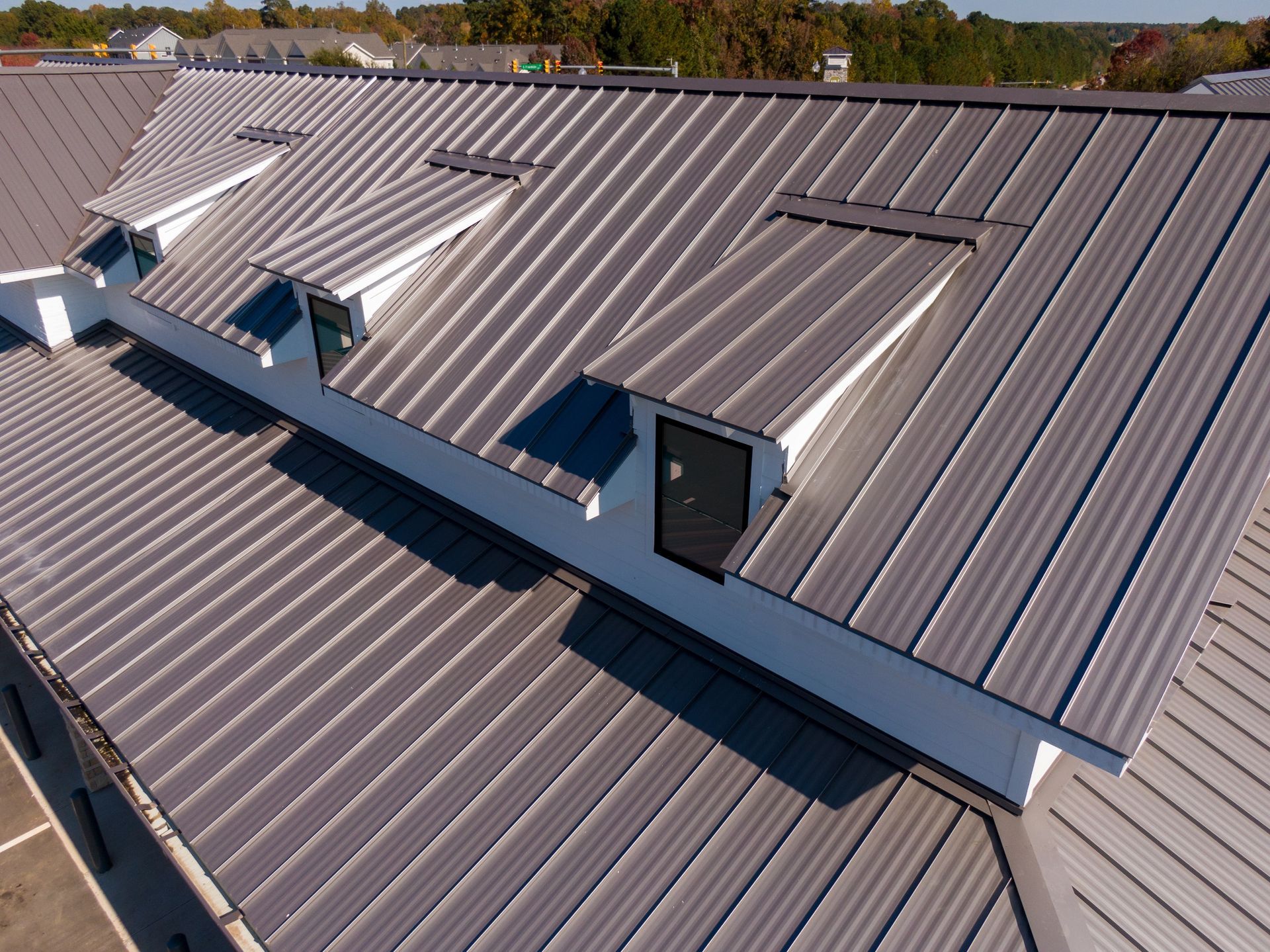 Rooftop with gray metal panels and several skylights under a clear sky