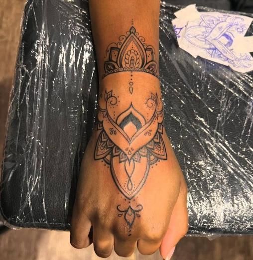 Hand with intricate black mandala tattoo, wrist to knuckles.