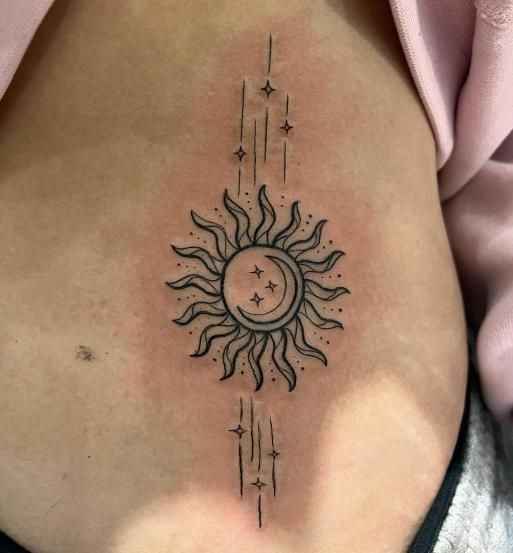 Sun and moon tattoo on skin, centered with stars and lines.