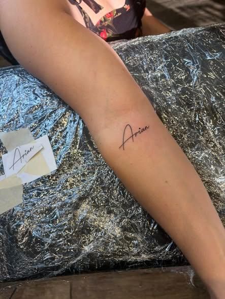 A tattoo on a forearm of the name 