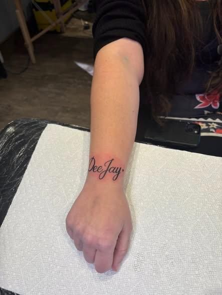 A person's forearm with a tattoo of the name 