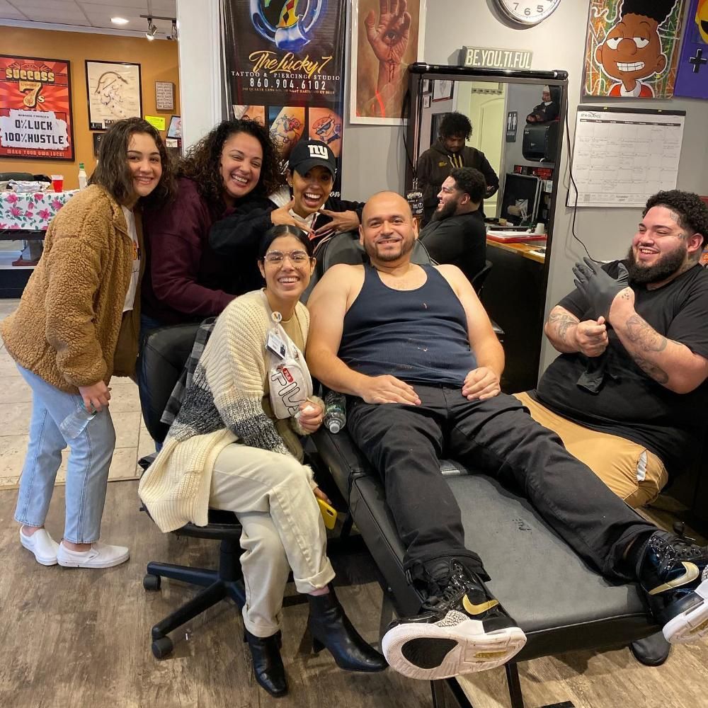 Group of people smiling in a tattoo parlor.