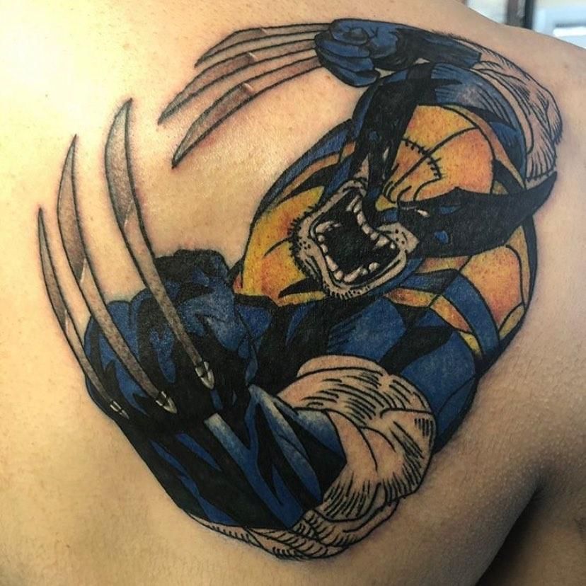 Tattoo of Wolverine, blue and yellow, with claws extended, roaring, on a back.