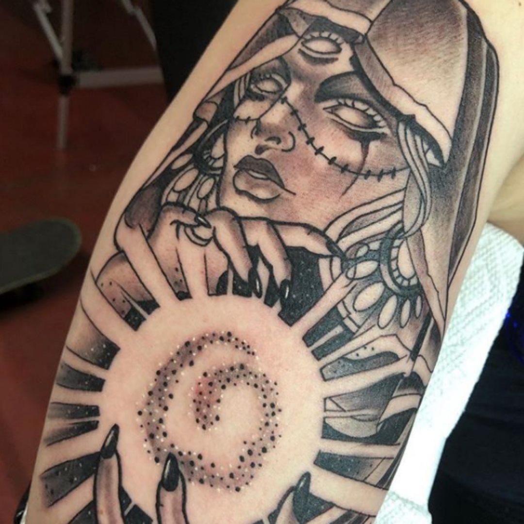 Tattoo of a hooded figure with glowing orb. 