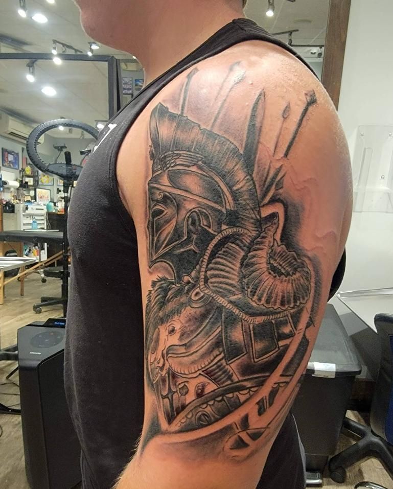 Tattoo of a gladiator warrior on a person's upper arm, inside a tattoo studio.