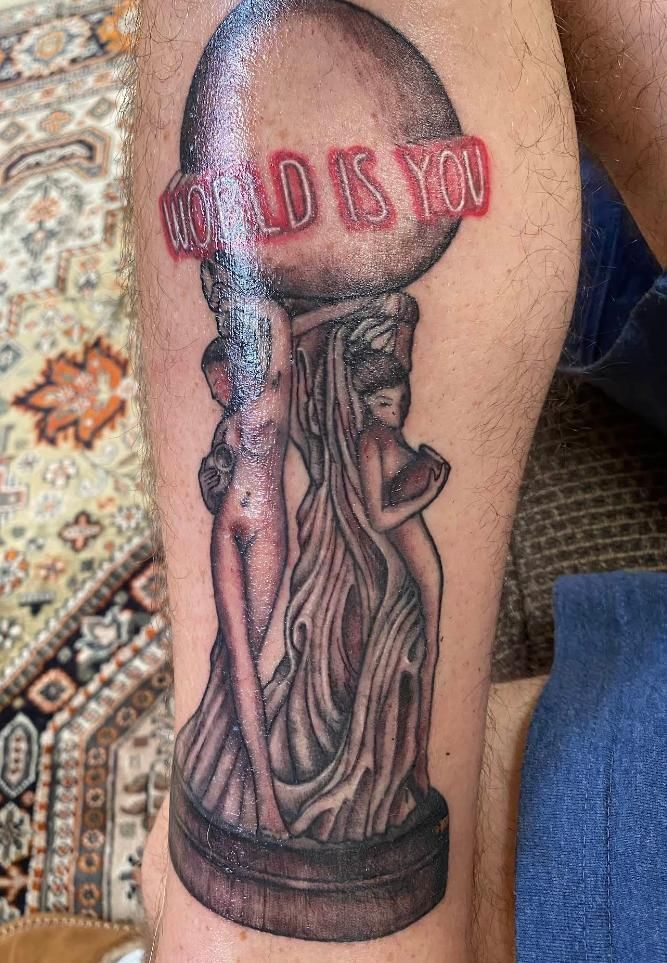 Tattoo of two female figures supporting a sphere with the words 