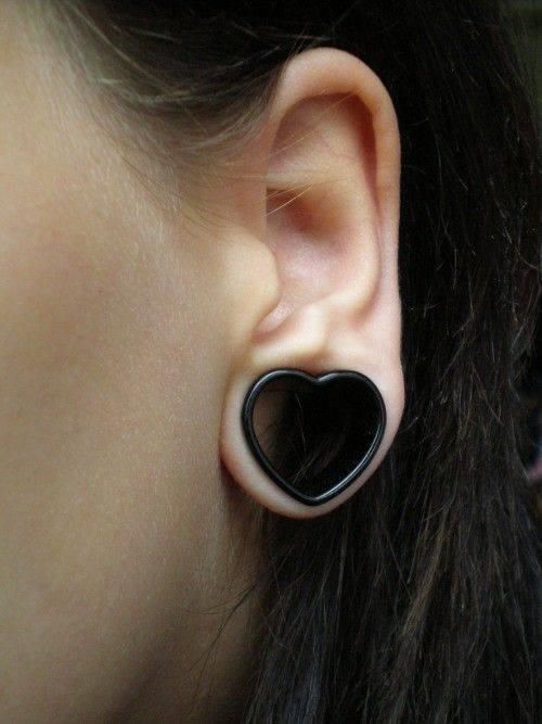 Close-up of a person's ear with a black heart-shaped ear gauge.