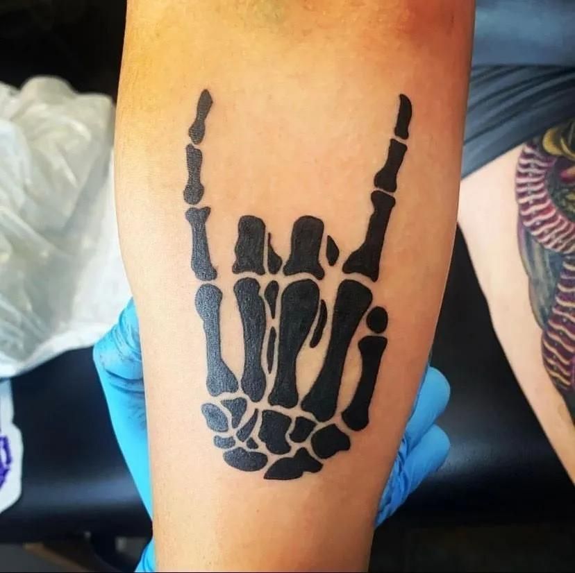 Black skeleton hand tattoo on a person's arm, making the 