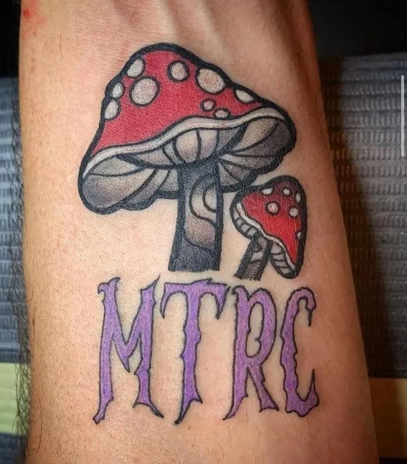 Tattoo of red mushrooms above the word 