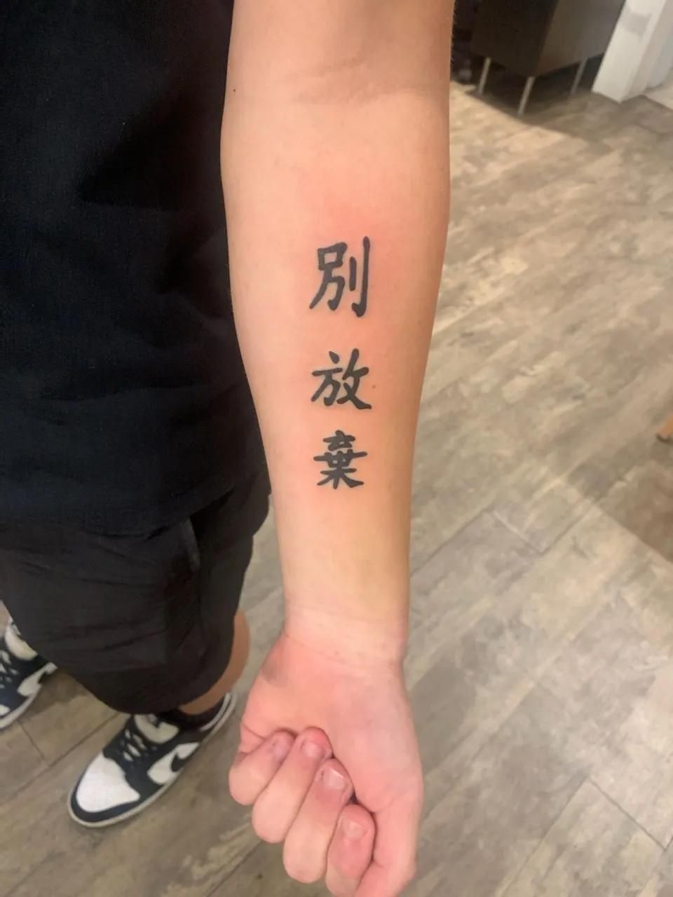 Arm with a tattoo of three Chinese characters.