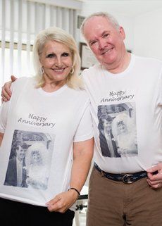 A man and a woman are standing next to each other wearing happy anniversary t-shirts.