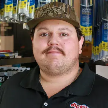 Man wearing a camo cap and black polo shirt with a mustache. He is smiling.