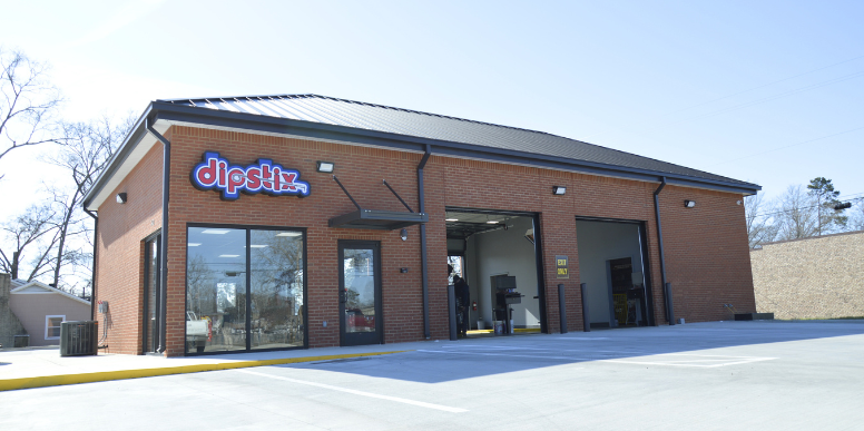 A Shell Rapid Lube gas station on a sunny day, with a clear blue sky and green landscaping.