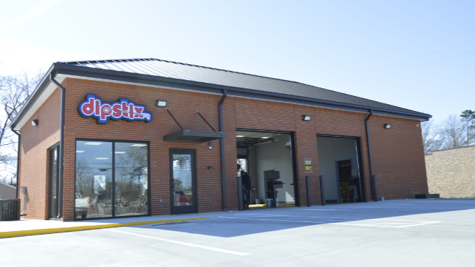 A Shell Rapid Lube gas station on a sunny day, with a clear blue sky and green landscaping.