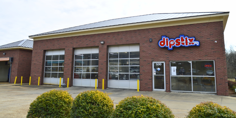 A Shell Rapid Lube gas station on a sunny day, with a clear blue sky and green landscaping.