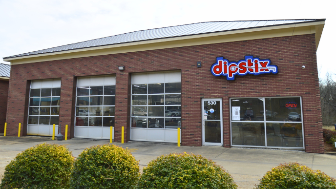 A Shell Rapid Lube gas station on a sunny day, with a clear blue sky and green landscaping.
