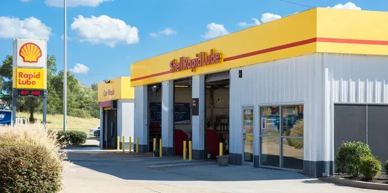 A Shell Rapid Lube gas station on a sunny day, with a clear blue sky and green landscaping.