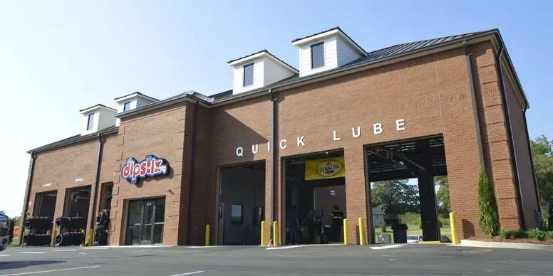 Exterior of Quick Lube auto shop; brick building with bays, signage, and a bright blue sky.