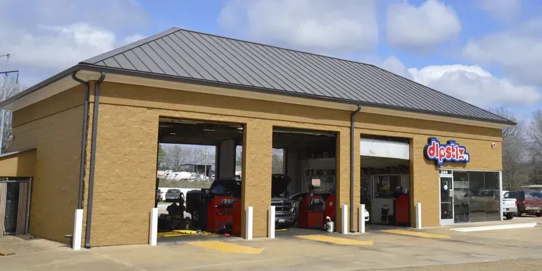 A Shell Rapid Lube gas station on a sunny day, with a clear blue sky and green landscaping.