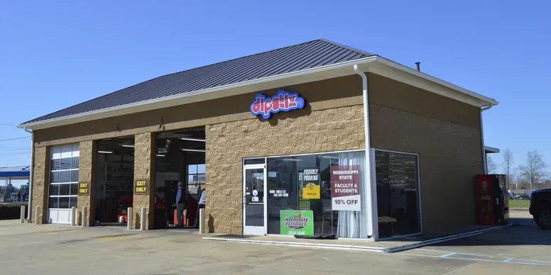 A Shell Rapid Lube gas station on a sunny day, with a clear blue sky and green landscaping.