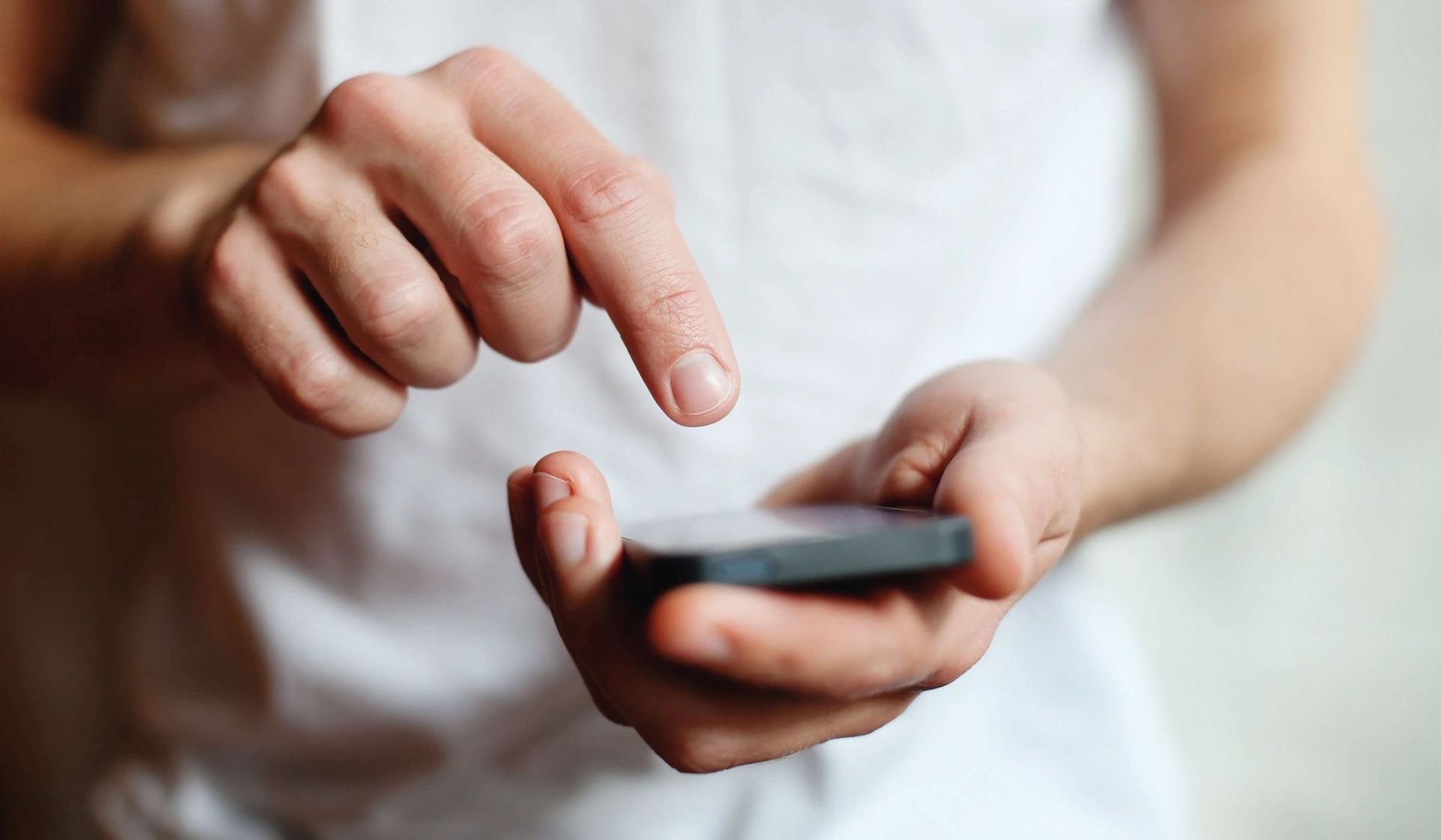 Person holding and tapping a smartphone screen with one finger.