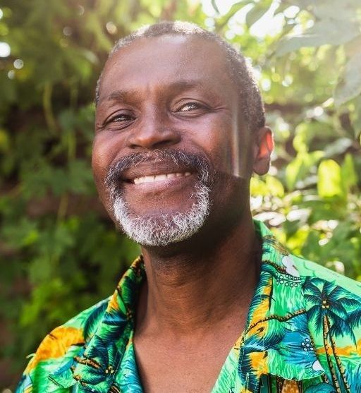 Smiling older person wearing a cap and sweater.
