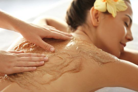 Client receiving sugar scrub on her back and shoulders