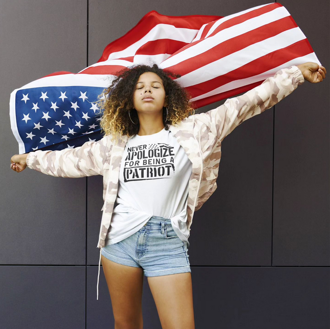 A woman wearing a patriotic t-shirt is holding an american flag