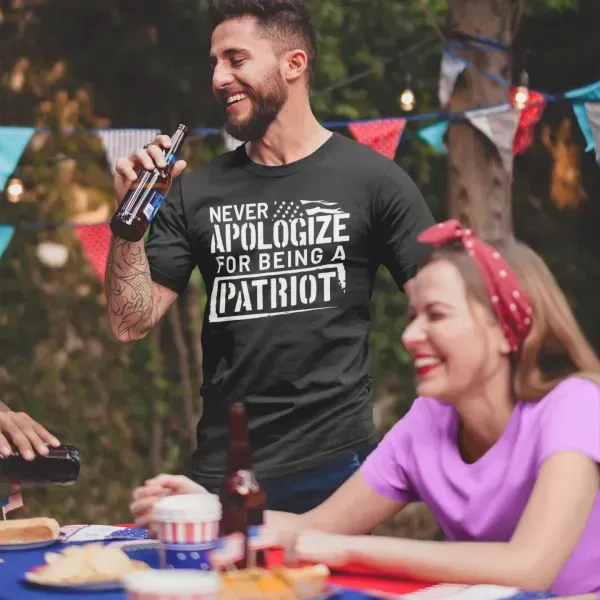 A man is holding a bottle of beer and wearing a shirt that says never apologize for being a patriot.