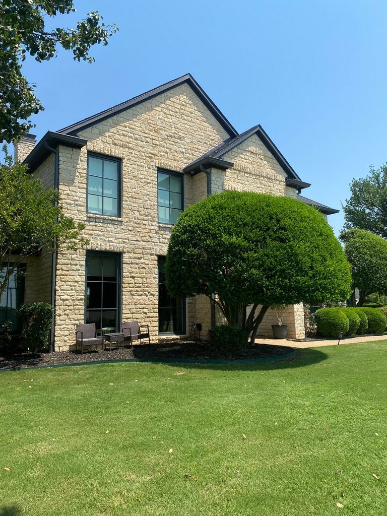 A large brick house with a large lawn in front of it.