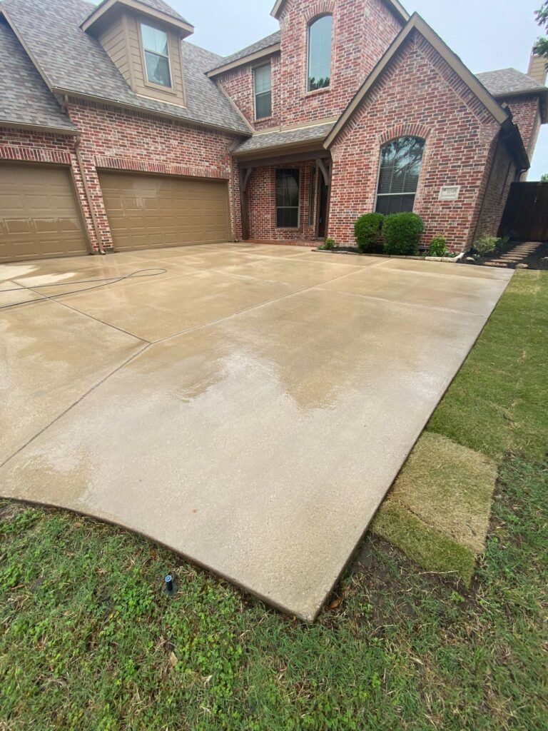 A large brick house with a concrete driveway in front of it.