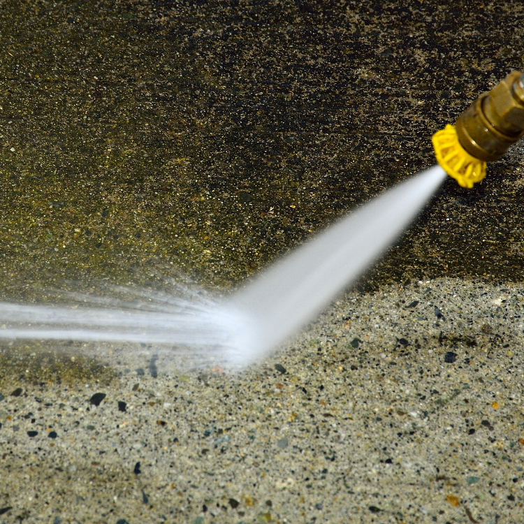 A close up of a high pressure washer spraying water on a concrete surface.