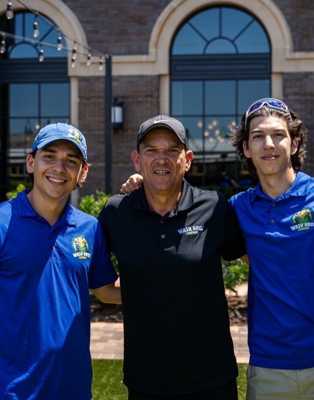 Three men are posing for a picture in front of a building