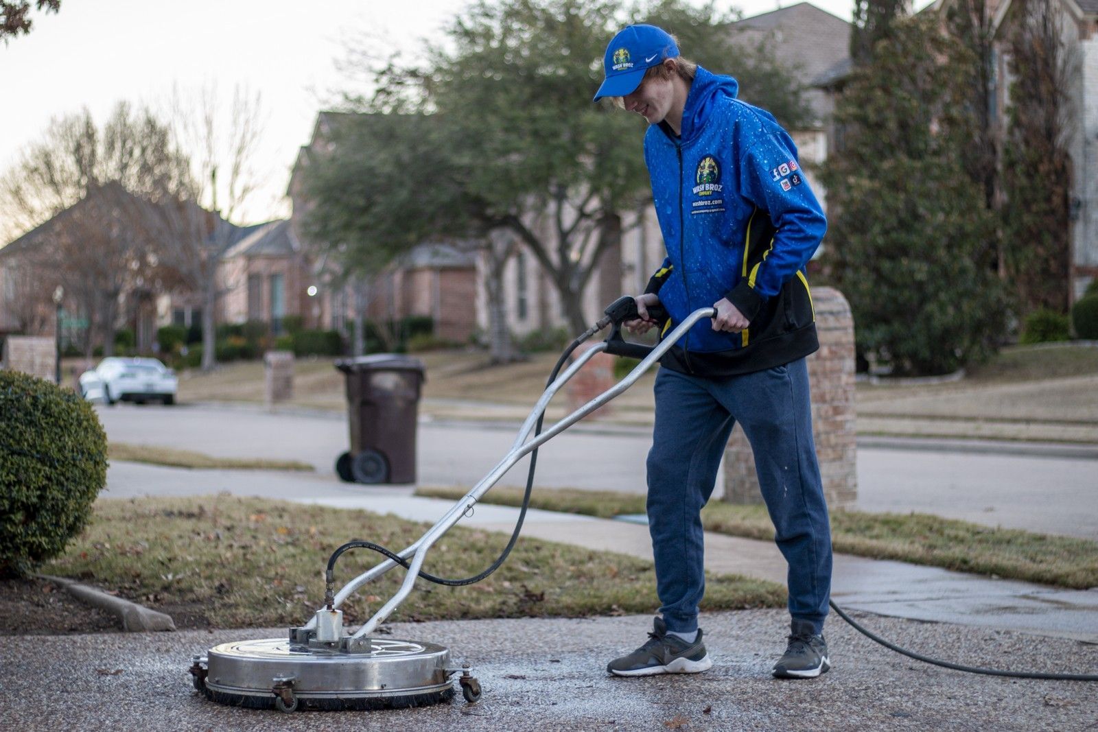 A man is cleaning a driveway with a machine.