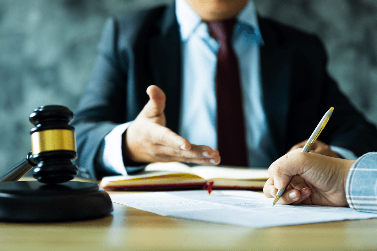 A man in a suit and tie is sitting at a table with a judge 's gavel.