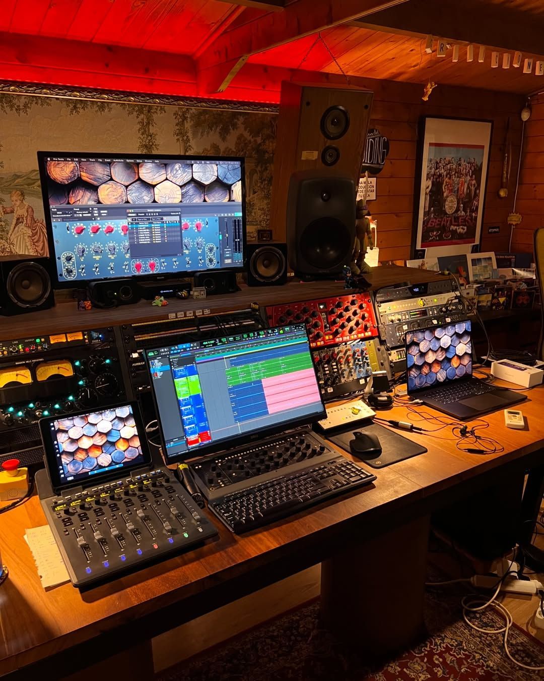 Un estudio de grabación con computadoras portátiles, monitores y mezcladores sobre una mesa.