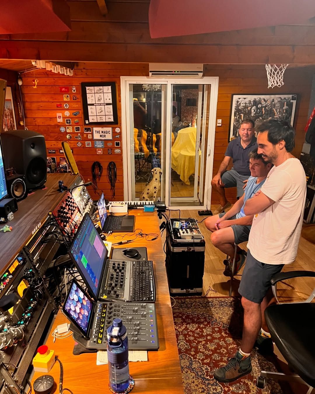 Un grupo de hombres está de pie alrededor de un escritorio en un estudio de grabación.