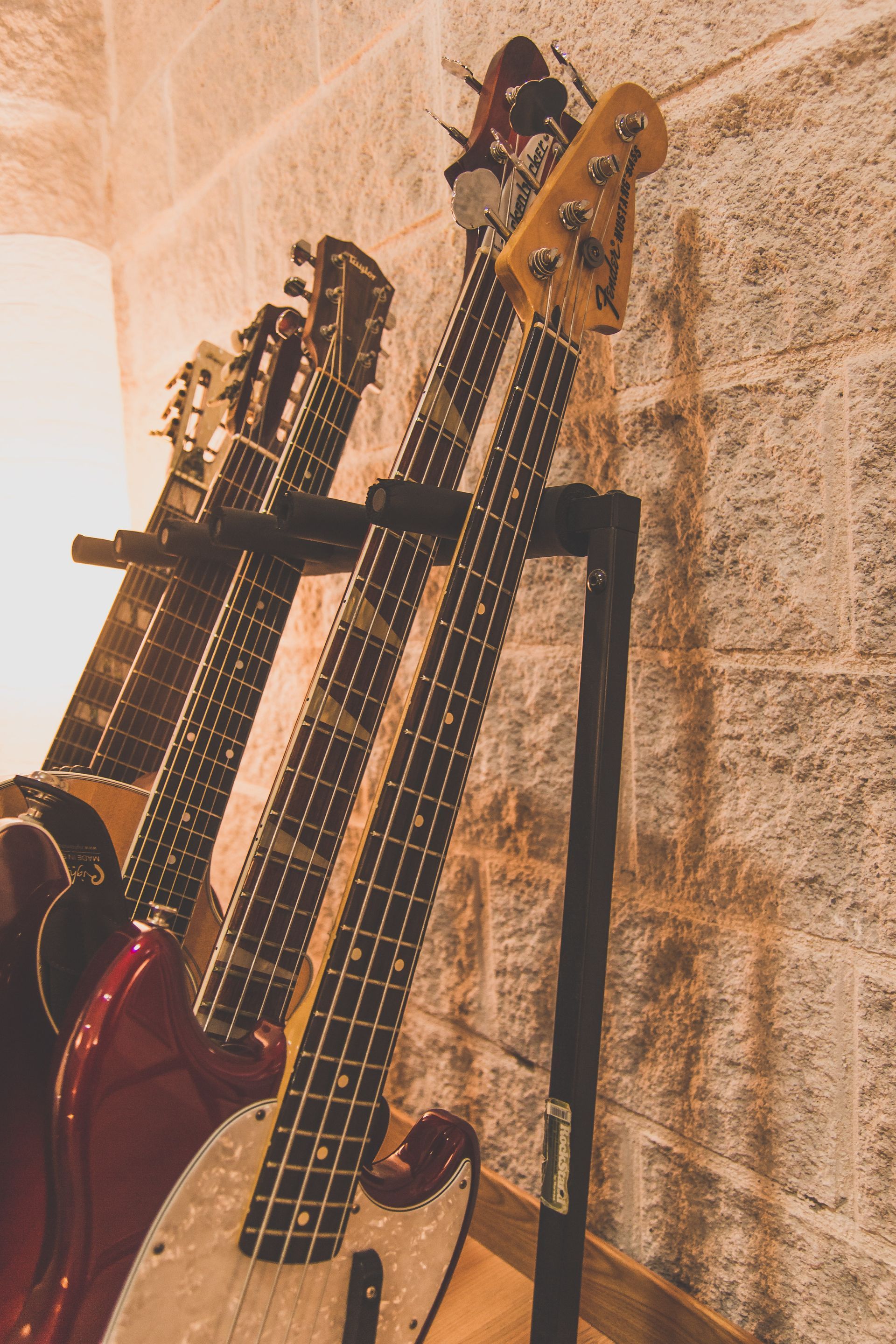 Tres guitarras están colocadas en un soporte contra una pared de ladrillos.