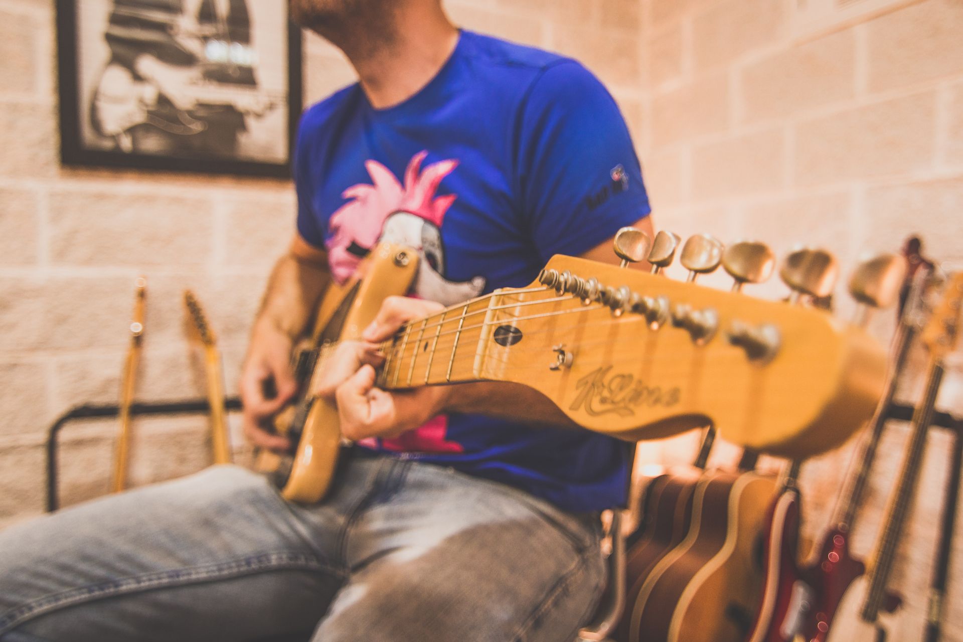 Un hombre con una camisa azul está tocando una guitarra eléctrica.