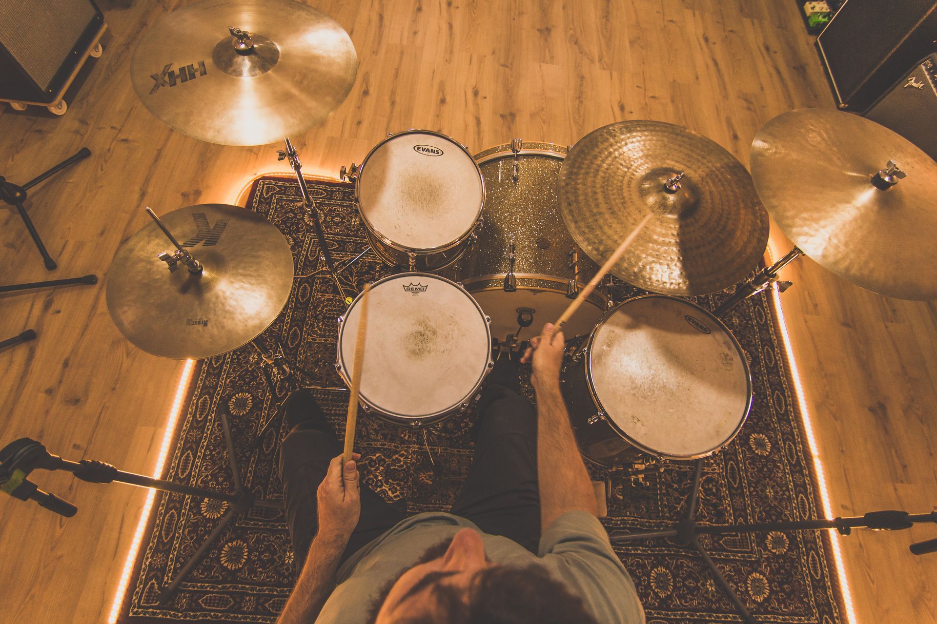 Un hombre está sentado en el suelo tocando la batería.