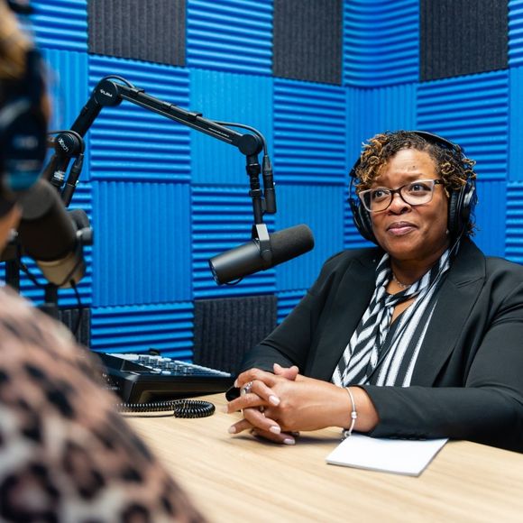 A woman wearing headphones is sitting in front of a microphone
