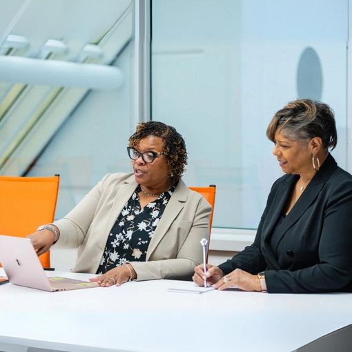Two women are sitting at a table with a laptop