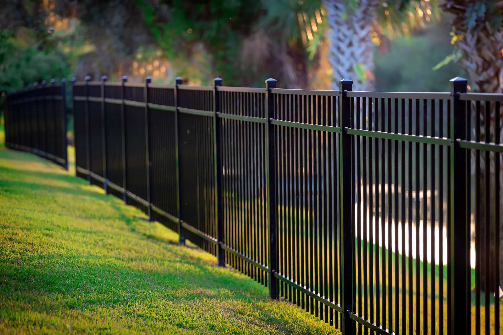 black metal fence surrounds a lush green field.
